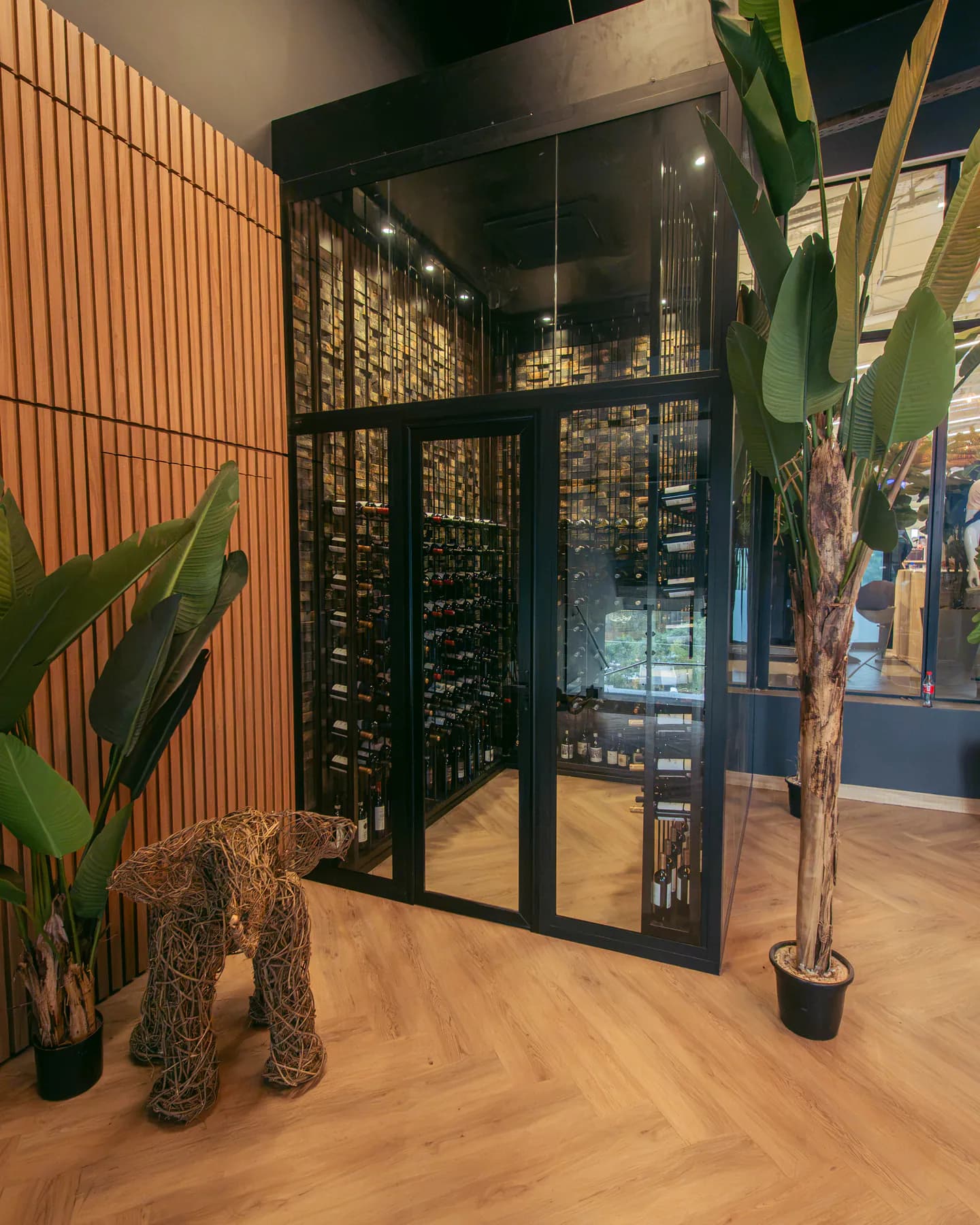 La cava de vinos vista desde el pasillo, con la jirafa de mimbre y una strelitzia