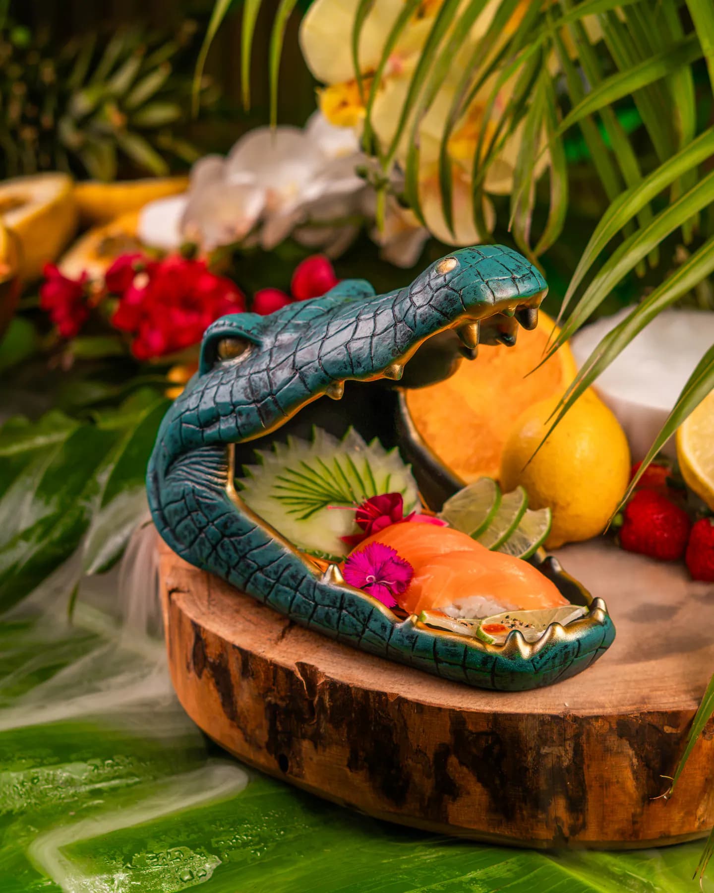 Piezas de sushi servidas en una fuente con forma de cocodrilo azul sobre hojas tropicales