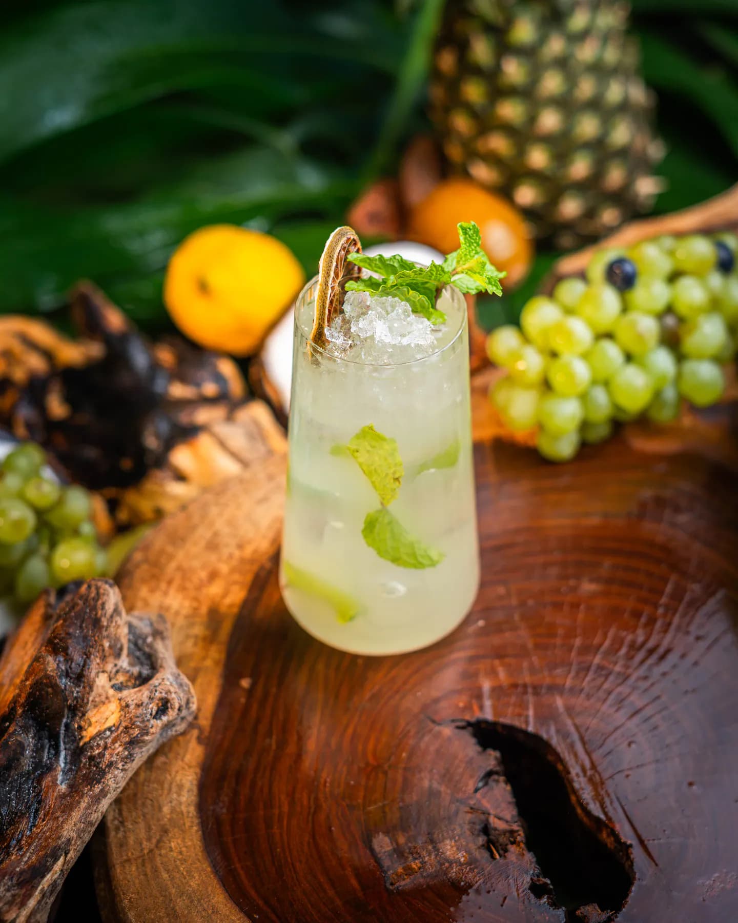 Mojito con menta y hielo frappé en vaso alto sobre un tronco